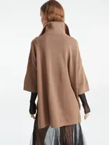 Poncho tejido de punto color negro con escote en V y cuello tipo polo. Presenta un diseño holgado con mangas tres cuartos.