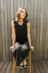 Chaleco negro con cuello redondo y espalda irregular. Detalle de plumas en los hombros.