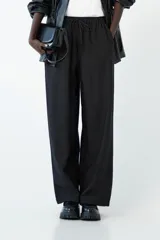 Pantalón negro de tiro bajo con cintura elástica y cordón ajustable, de corte ancho y largo hasta el tobillo.