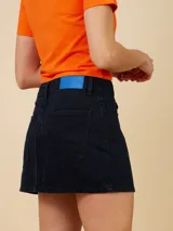 Minifalda de denim celeste con corte asimétrico y cierre con botón metálico.