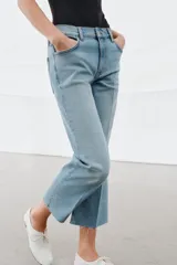 Jeans de tiro medio con corte flare y largo cropped. Presentan diseño de cinco bolsillos, cierre frontal con cremallera y botón, raya planchada en el delantero y bajo desflecado con acabado evasé.