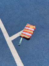 Sobre de mano rectangular con cierre superior y correa de muñeca, con diseño a rayas horizontales en tonos naranja, rojo, verde y celeste.