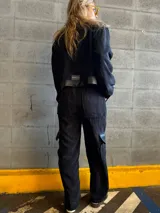 Conjunto negro de pana compuesto por una chaqueta con cuello de cuero sintético, cierre frontal con cremallera y bolsillos con solapa, y un pantalón de corte recto con bolsillos laterales.