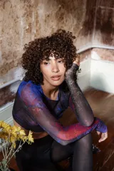 Top corto de tul estampado con diseño abstracto en tonos azul, rojo y negro, de mangas largas y corte ajustado.