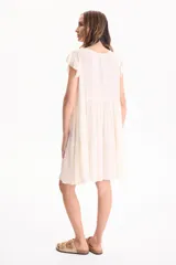 Vestido corto de viscosa color beige, sin mangas con volados en las sisas, escote en V y diseño escalonado.