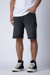 Bermuda de jean color negro lavado, de corte regular y largo a la rodilla, con dobladillo doblado en el ruedo.