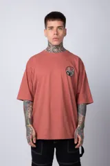 Remera de corte oversize color terracota, con cuello redondo y manga corta. Presenta un estampado circular pequeño en el pecho con motivos orientales.