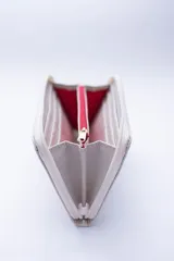 Billetera rectangular con cierre perimetral, confeccionada en cuero con textura de reptil. Cuenta con múltiples compartimentos internos para tarjetas, documentos y billetes, además de un bolsillo interior con cierre para monedas.