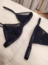Conjunto de lencería compuesto por un corpiño triangular de microtul transparente con detalles de encaje en las copas y una tanga regulable de elástico ancho.