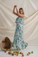 Vestido largo de gasa plisada con estampado floral en tonos verde, celeste, blanco y rosa. Diseño strapless con volado en el corsé, corte en la cintura y falda amplia.