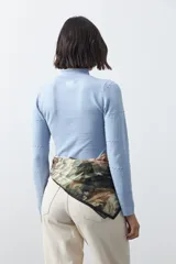 Polera de tejido de punto color celeste, con cuello alto y textura de pequeños puntos en relieve formando una cuadrícula en el frente y las mangas. De corte ajustado y manga larga.