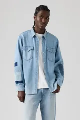 Camisa de jean estilo western con diseño de parches tipo sashiko en las mangas. Presenta cuello clásico, cierre frontal con botones a presión, dos bolsillos en el pecho con solapa y puños abotonados.