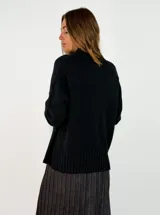 Sweater de punto color marrón chocolate, con cuello alto y puños y ruedo acanalados. Presenta un diseño holgado y mangas largas.