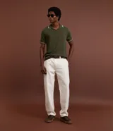 Camisa polo de manga corta color verde oliva, confeccionada en tejido de punto, con cuello y puños con ribetes contrastantes en blanco y rojo.