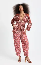 Kimono de punto Le Lis Blanc modelo Bina, con patrón jacquard geométrico en tonos rosados, marrones y crudo. Presenta escote en V profundo con ribete acanalado, mangas anchas de largo medio, corte holgado y cinturón de la misma tela para atar en la cintura.