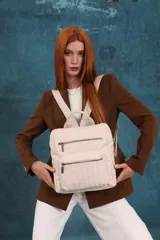 Mochila urbana de tamaño mediano confeccionada en símil cuero, con diseño de costuras verticales en el bolsillo frontal. Cuenta con dos compartimentos principales con cierre, asa superior y correas ajustables.