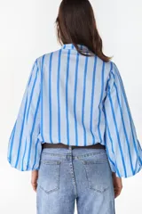 Camisa de manga larga abullonada con diseño a rayas verticales celestes y azules, cuello mao y cierre frontal con botones ocultos.