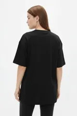 Remera de algodón negro con cuello redondo y diseño holgado, con estampado frontal de líneas horizontales blancas y un corazón rojo superpuesto.