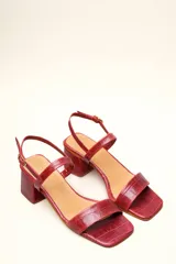 Sandalia de cuero vacuno color negro con textura de cocodrilo, taco cuadrado de 4 cm, punta cuadrada y dos tiras finas, una en el empeine y otra con hebilla en el tobillo.