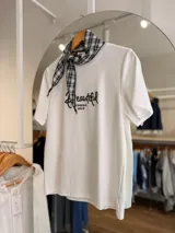 Remera blanca de manga corta, con cuello redondo y diseño holgado. Cuenta con un bordado frontal en negro con la palabra "Beautiful" y texto complementario. Incluye un pañuelo de cuello con patrón a cuadros blanco y negro.
