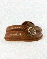 Sandalias de cuero color negro, de diseño plano con una tira ancha en el empeine y una hebilla metálica dorada grande como detalle.