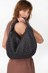 Bolso tipo hobo de cuero marrón oscuro, con diseño trenzado y asa integrada al hombro.