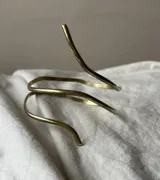 Brazalete rígido en forma de espiral de metal plateado.