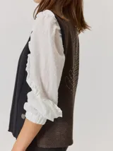 Chaleco de paño con diseño bicolor, frente en color negro y espalda en color marrón con textura de espiga. Presenta un maxi bordado de hoja en la parte posterior y detalles de tejido en los bordes.