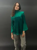 Buzo verde esmeralda de lana merino con cuello alto y mangas largas. Presenta dos texturas: afieltrada en cuello, mangas y ruedo, y tejido merino superfino en el delantero y la espalda.