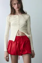 Shorts de tiro medio confeccionados en satén rojo, con diseño tipo globo y cintura elástica ajustable mediante cordones. Presentan detalles de encaje blanco en los laterales.