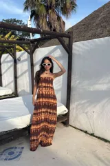 Vestido largo strapless de fibrana con estampa tie-dye en tonos marrones y beige, con espalda baja descubierta y diseño entallado al cuerpo.