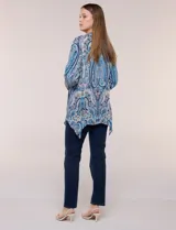 Blusa holgada de poliéster con estampado de arabescos en tonos azules, escote en V con botones frontales, mangas 3/4 y ruedo asimétrico en punta.
