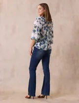 Blusa estampada con flores azules y verdes, cuello a la base con escote en V y volados. Manga larga con puño y apliques de puntilla.