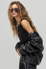 Chaqueta de cuero negro con diseño oversized, hombros estructurados y apliques geométricos en el pecho.