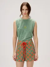 Musculosa crop de algodón en color verde con efecto acid wash, cuello redondo y pequeño gráfico bordado en el centro del pecho.