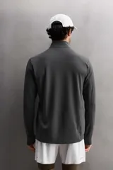 Camiseta de manga larga negra, confeccionada en tejido técnico ligero y elástico. Tiene cuello alto con cremallera, corte slim fit, bolsillo frontal con cremallera y puños con cinta a contraste.