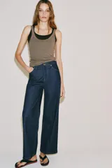 Jeans wide leg de tiro alto en color azul oscuro, con trabillas en la cintura, diseño de cinco bolsillos, nervios delanteros marcados y pespuntes a contraste. Cuenta con cierre frontal de cremallera y botón metálico.