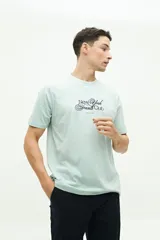 Remera clásica de manga corta, color verde menta, con estampado frontal que dice "New York Tennis Club" y "Brooksfield" en azul marino.