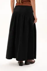 Pollera larga de color negro, con corte a la cadera y falda con frunce que aporta volumen y movimiento. Confeccionada en tela suave con acabado tipo piel de durazno.