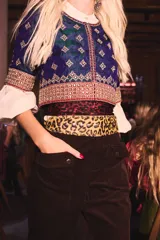 Cinturón tipo faja de cuero con estampado animal print de leopardo, decorado con tachas metálicas circulares a lo largo de toda la pieza.