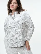 Buzo de dormir de tela fleece con estampado animal print en tonos grises y blancos. Presenta cuello alto con cierre de botones a presión y mangas largas.
