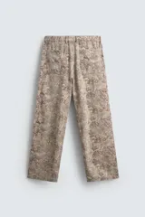 Pantalón de corte relajado confeccionado en tejido ligero de algodón con estampado abstracto de efecto lavado. Presenta cintura elástica, bolsillos frontales y bolsillos traseros de plastrón, con cierre frontal de cremallera y botón.