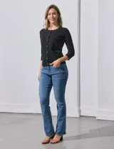 Cardigan blanco de tejido fino con abertura central y botones.