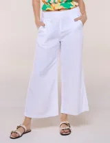 Pantalón crop de lino y rayón, con diseño wide leg de corte holgado, estampado tropical de hojas en tonos verde, azul y marrón sobre fondo blanco. Cuenta con pretina trasera elastizada y bolsillos delanteros.