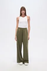 Pantalon deportivo de corte ancho y tiro alto, color verde oliva, con cintura elástica y una línea vertical blanca lateral en cada pierna.