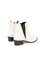 Bota de cuero vacuno liso color blanco hueso, con elásticos laterales negros, taco recto de 4 cm y suela de goma antideslizante.