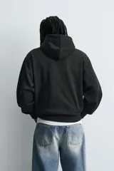 Sudadera tipo hoodie de corte relajado, confeccionada en tejido de algodón con interior cepillado. Presenta capucha con cordones ajustables, bolsillo frontal tipo canguro y terminaciones en rib en puños y ruedo.