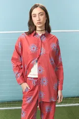 Camisa de algodón color rojo con estampado de soles en color azul, de corte oversize, cuello camisero y mangas largas.