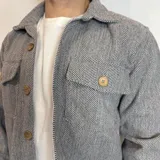 Sobrecamisa gris con patrón de espiga, cuello clásico, cierre con botones de madera, dos bolsillos de parche en el pecho y corte recto.