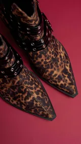 Botín de gamuza con estampado de leopardo, punta fina y apliques de correas de cuero sintético negro con hebillas metálicas.